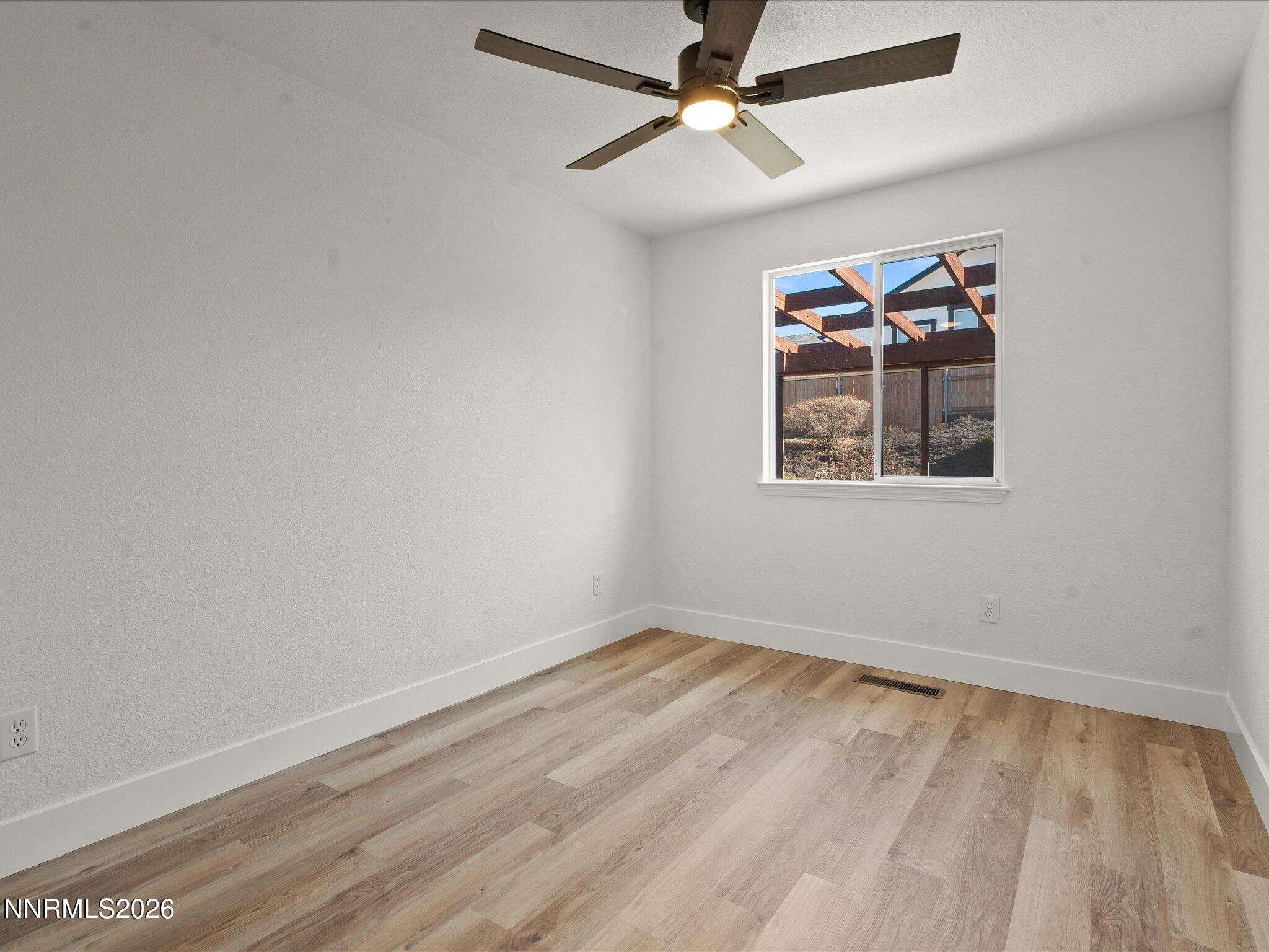 3549 Shadow Lane Carson City, NV 89705 - Photo 17 of 32 an empty room with wooden floor ceiling fan and windows