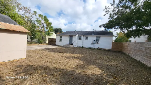 a view of a white house with a big yard and large trees