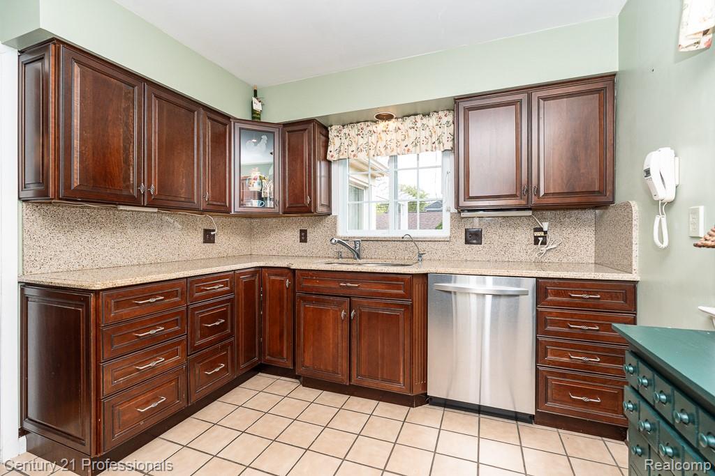 304 Highland Avenue Rochester, MI 48307 - Photo 8 of 30 Kitchen featuring rich wood cabinetry, light-toned countertops, a stainless steel dishwasher, and a window above the sink