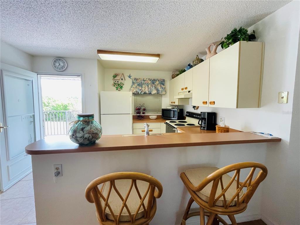 25100 Sandhill Boulevard, Unit Q201 Punta Gorda, FL 33983 - Photo 8 of 25 a kitchen with stainless steel appliances a sink and a dining table with wooden floor