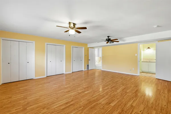 a view of empty room with wooden floor and fan