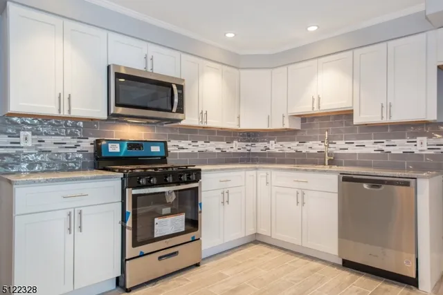 a kitchen with stainless steel appliances granite countertop grey cabinets a stove a sink and a microwave