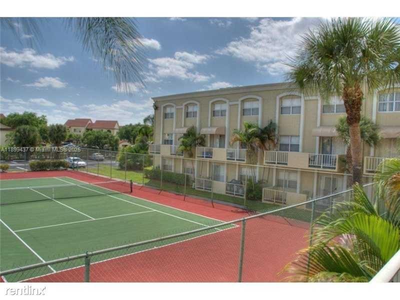 18111 Northwest 68th Avenue, Unit F203 Hialeah, FL 33015 - Photo 14 of 15 a view of outdoor space and tennis court