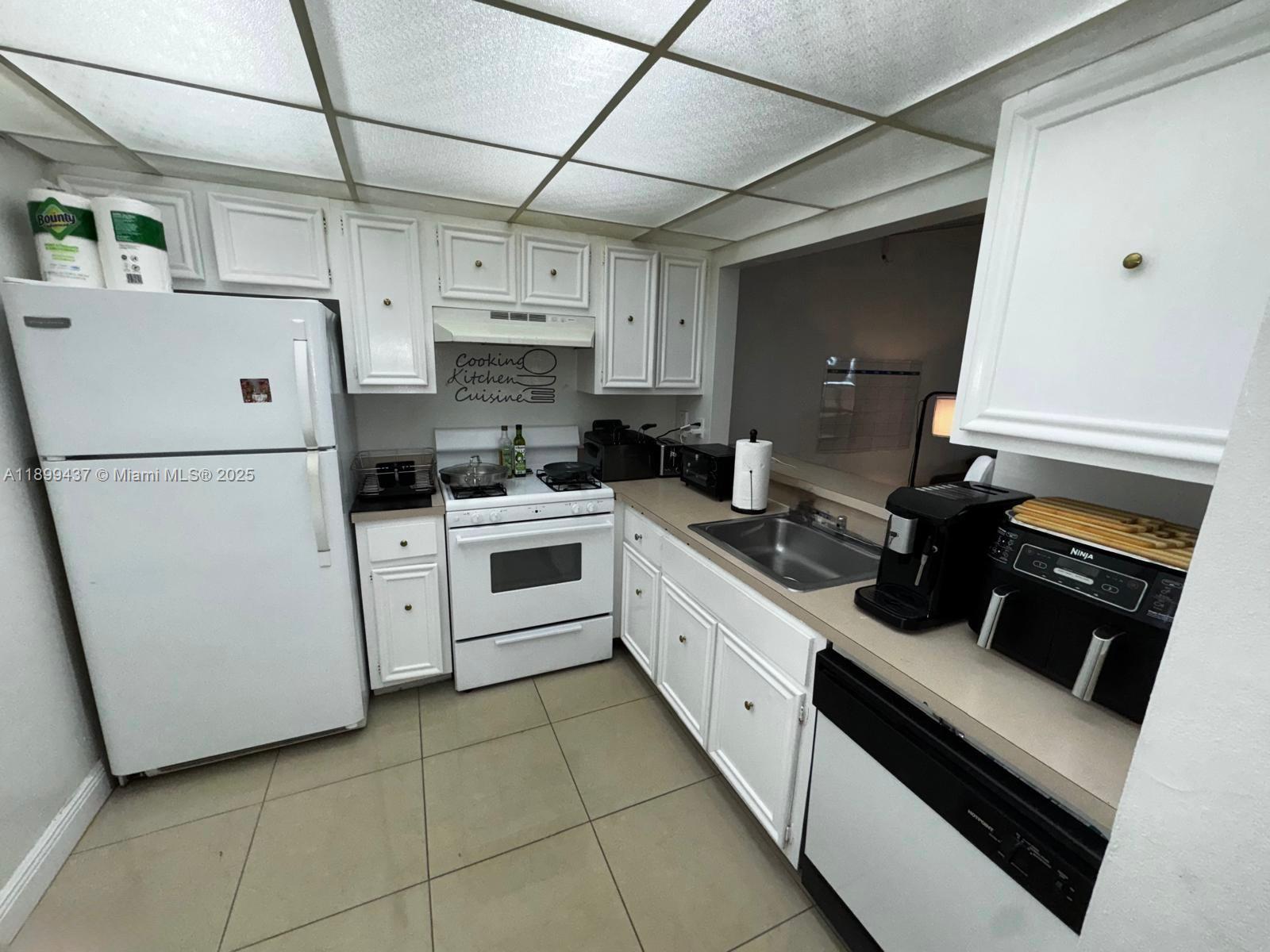 18111 Northwest 68th Avenue, Unit F203 Hialeah, FL 33015 - Photo 7 of 15 a kitchen with a sink a stove and refrigerator