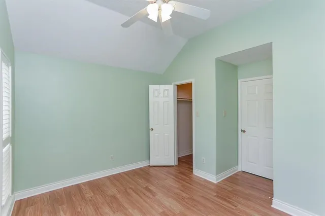 an empty room with wooden floor and a ceiling fan