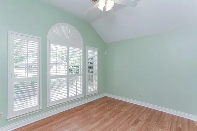 a view of empty room with wooden floor and fan