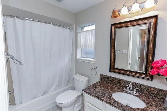 a bathroom with a granite countertop sink toilet mirror and a shower
