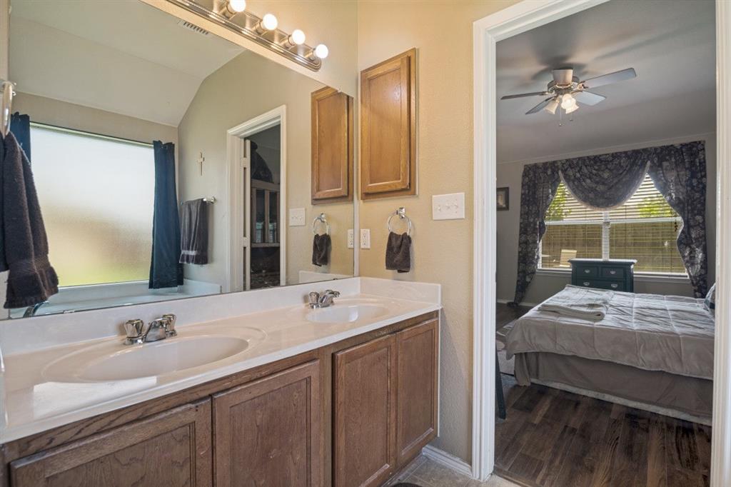 119 Robin Lane Forney, TX 75126 - Photo 17 of 27 Bathroom vanity featuring dual sinks with chrome faucets, a white countertop, and wood-finish cabinetry
