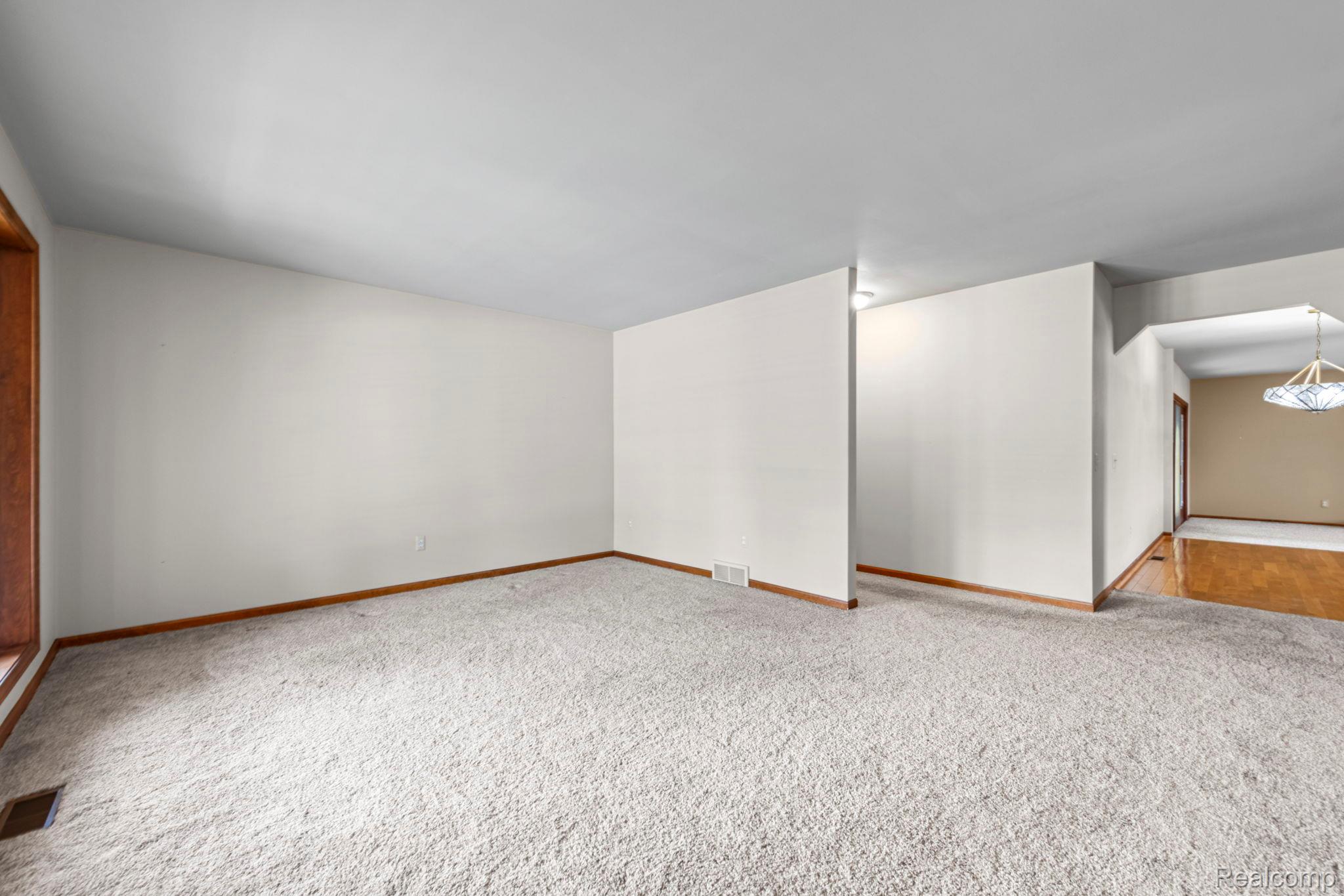 21580 Georgetown Road Trenton, MI 48183 - Photo 7 of 36 Spacious room featuring light-colored carpeting, white wall finishes, and wood trim details