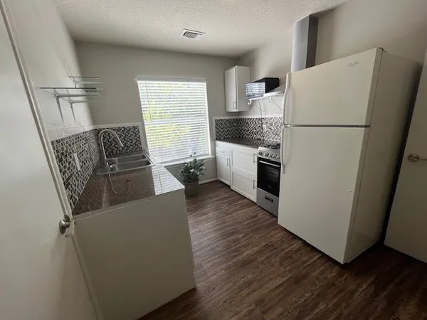 a kitchen with a refrigerator a stove top oven and wooden floor