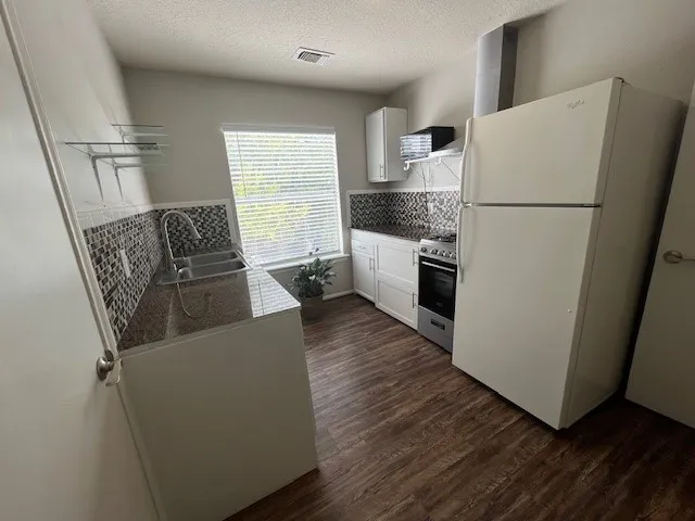 a kitchen with a refrigerator a stove top oven and wooden floor