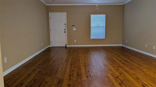 a view of an empty room with wooden floor and a window