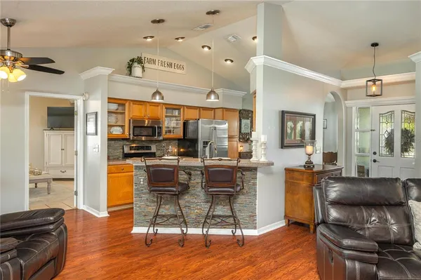 a kitchen with stainless steel appliances kitchen island granite countertop a refrigerator a stove top oven a dining table and chairs with wooden floor