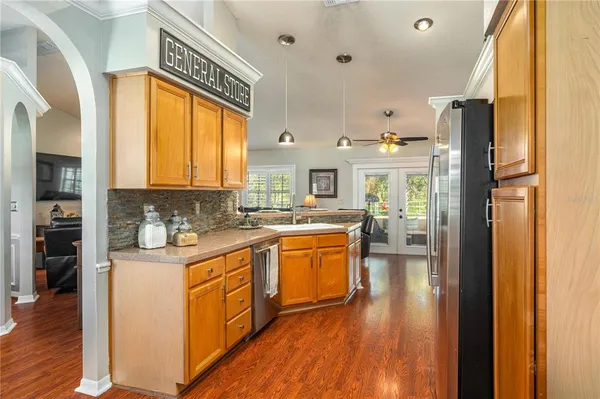 a kitchen with stainless steel appliances granite countertop a refrigerator a sink dishwasher a stove and a dining table with wooden floor