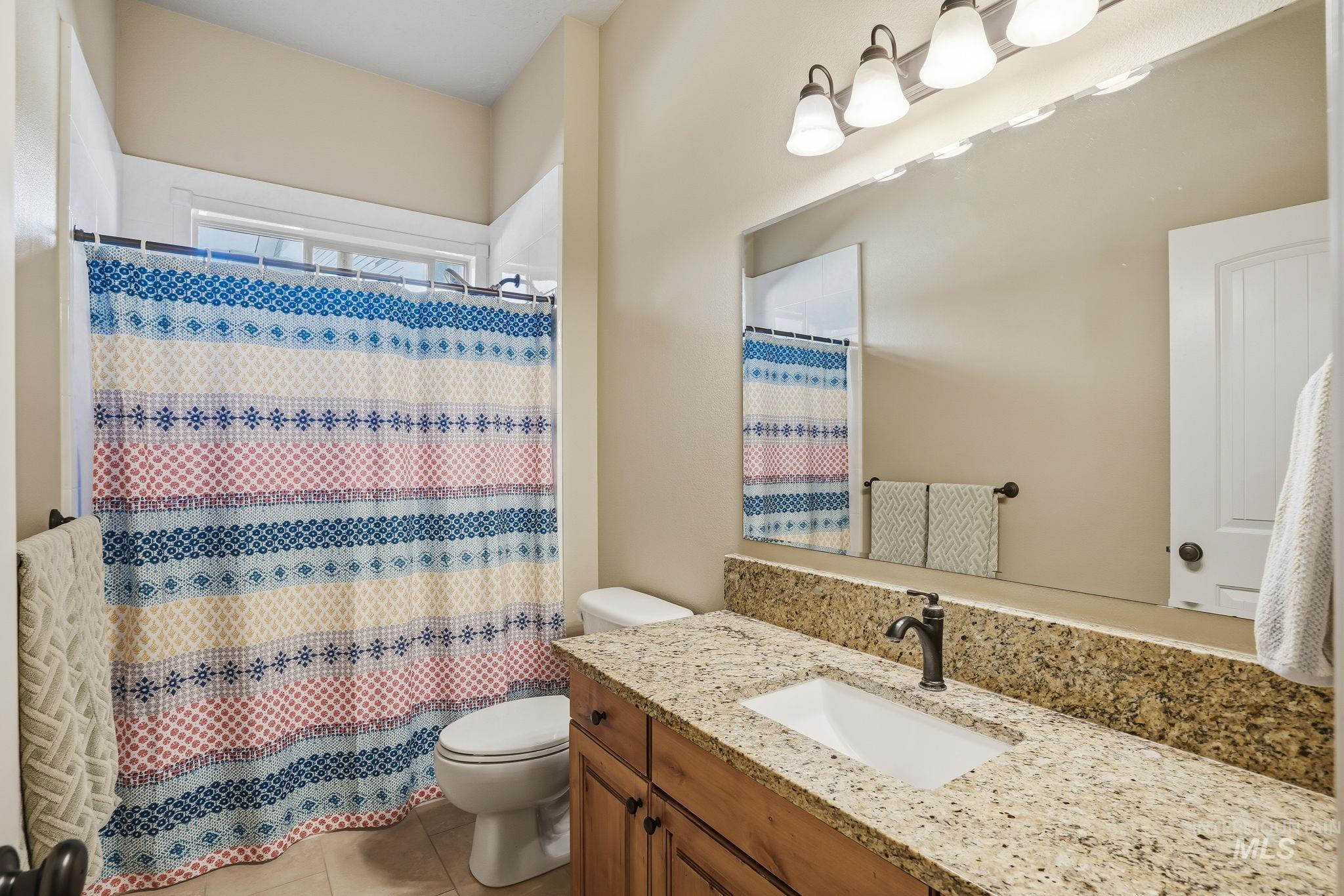 3969 North Hollymount Way Meridian, ID 83646 - Photo 29 of 47 Bathroom featuring a natural wood-finish vanity with a stone countertop, an undermount sink, and a dark bronze faucet