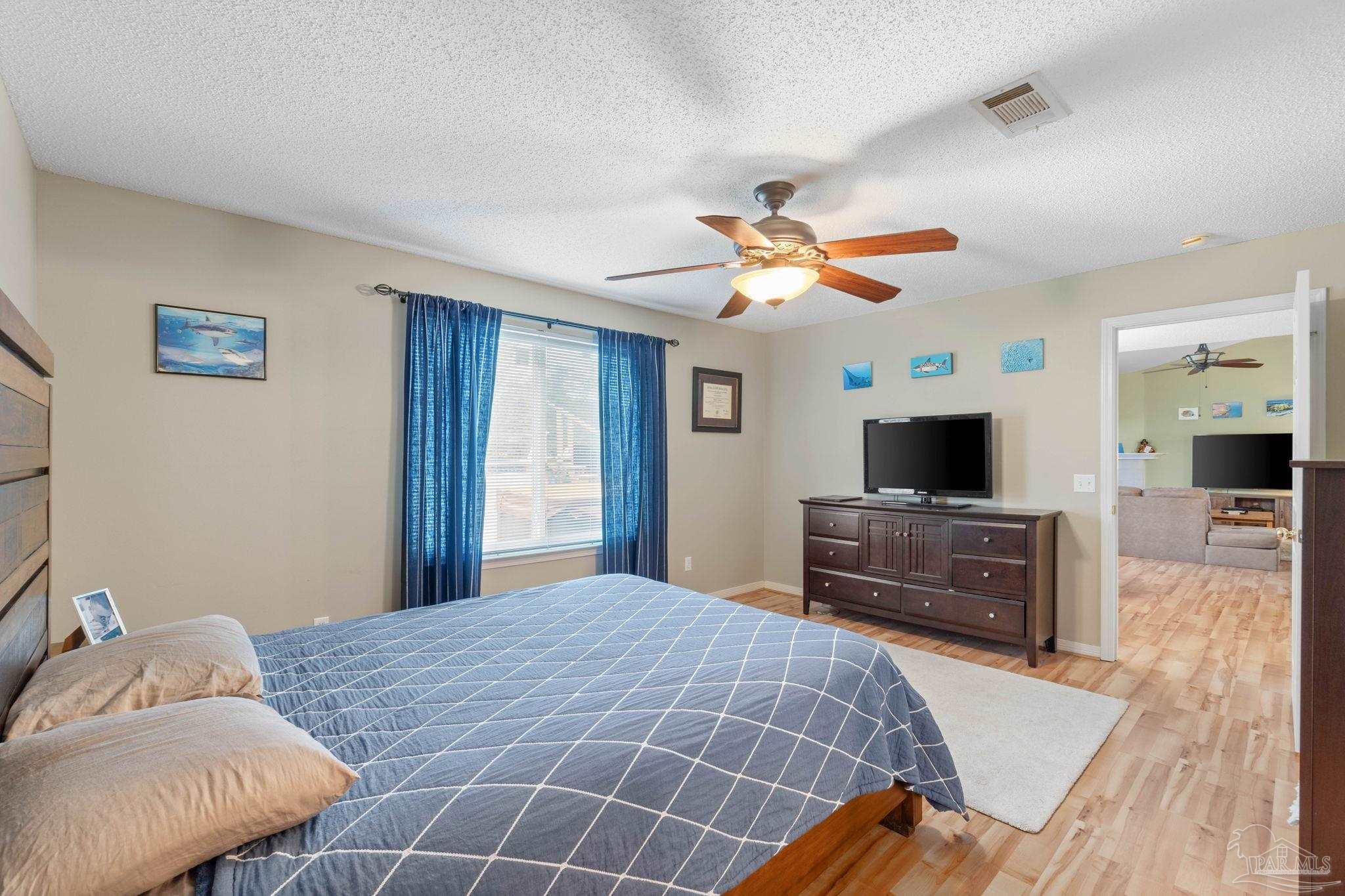 1342 Mazurek Boulevard Pensacola, FL 32514 - Photo 36 of 36 a bedroom with a large bed a flat tv screen and a chandelier