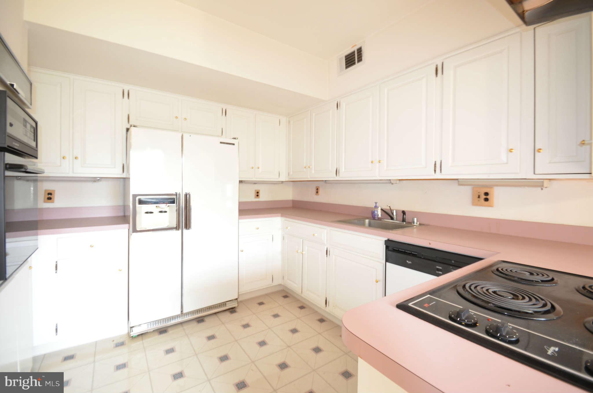 310 Ridgemede Road, Unit 206 Baltimore, MD 21210 - Photo 11 of 17 a kitchen with a stove a refrigerator and white cabinets
