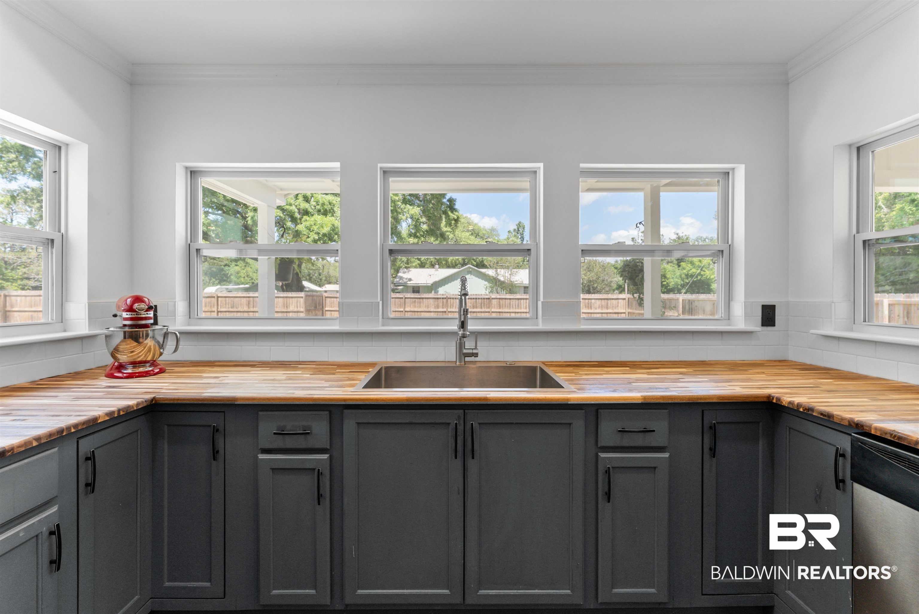 6447 Bemis Lane Bon Secour, AL 36511 - Photo 14 of 62 Kitchen featuring an undermount stainless steel sink, dark cabinetry, wood-finish countertops, and white subway tile backsplash