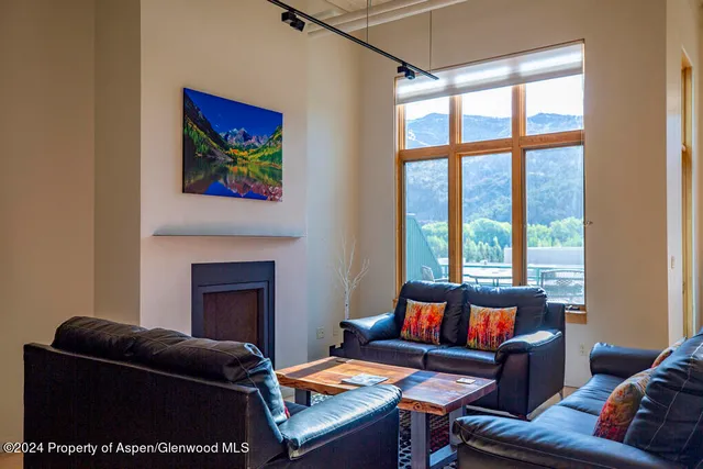 a living room with furniture a fireplace and a large window