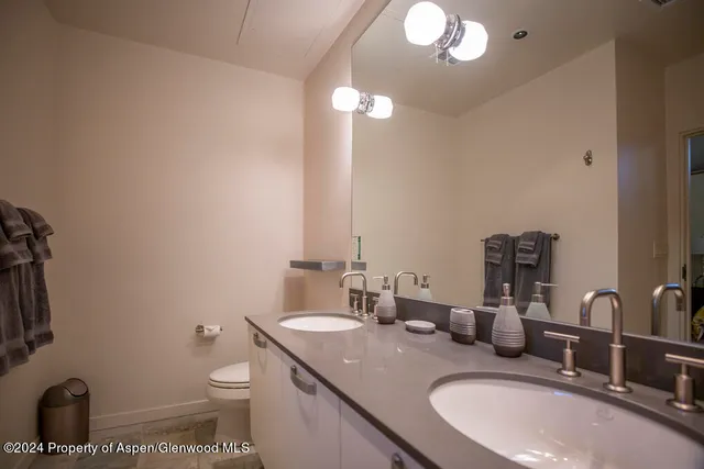 a bathroom with a granite countertop sink a toilet and a mirror