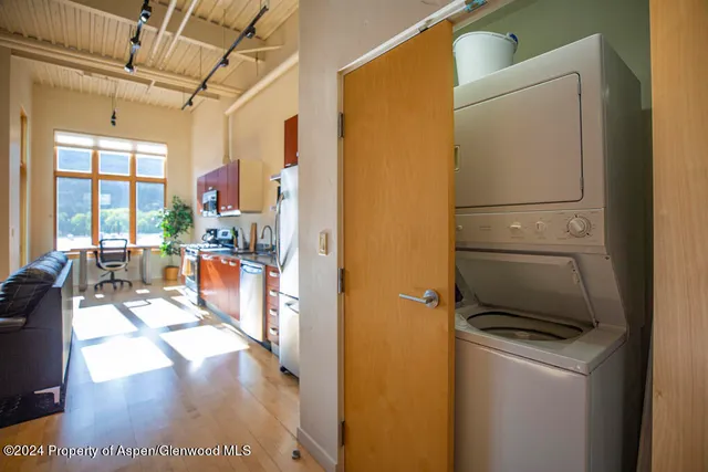 a kitchen with stainless steel appliances a refrigerator a stove a sink a dining table and chairs with the view of kitchen