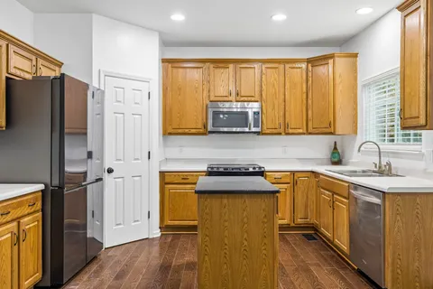 a kitchen with stainless steel appliances granite countertop a refrigerator a sink dishwasher and wooden cabinets with wooden floor