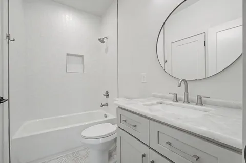 a bathroom with a granite countertop toilet a sink and a mirror