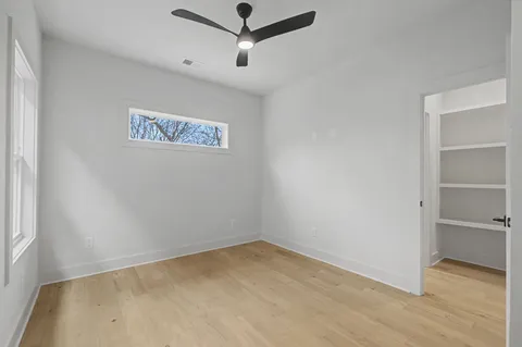an empty room with a ceiling fan and wooden floor