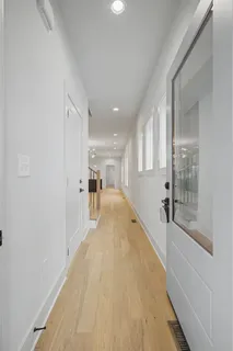 a view of a hallway with wooden floor and a living room