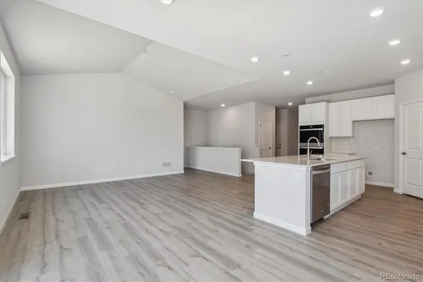 a view of kitchen with stainless steel appliances kitchen island wooden floors and white cabinets