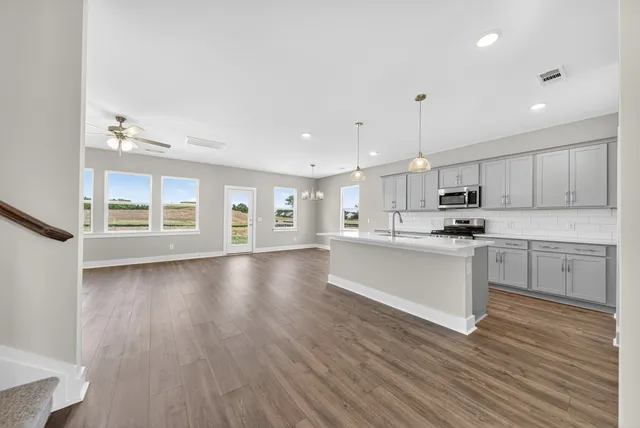 a kitchen with white cabinets and a stove with wooden floors