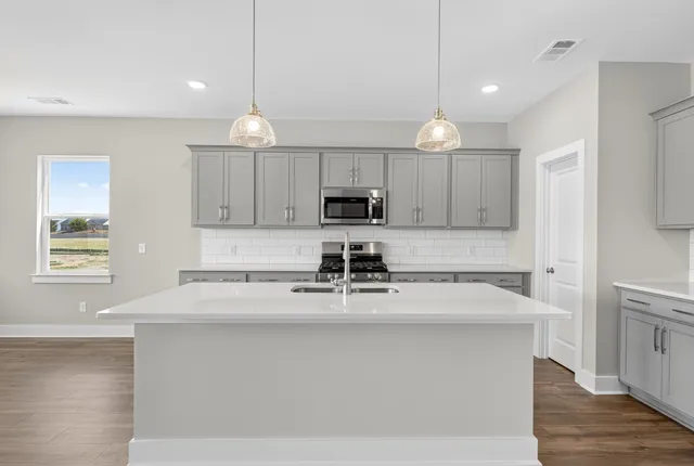 a kitchen with granite countertop white cabinets and wooden floor