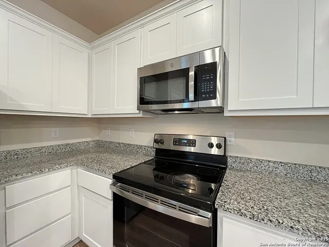 a kitchen with stainless steel appliances granite countertop white cabinets and a stove top oven