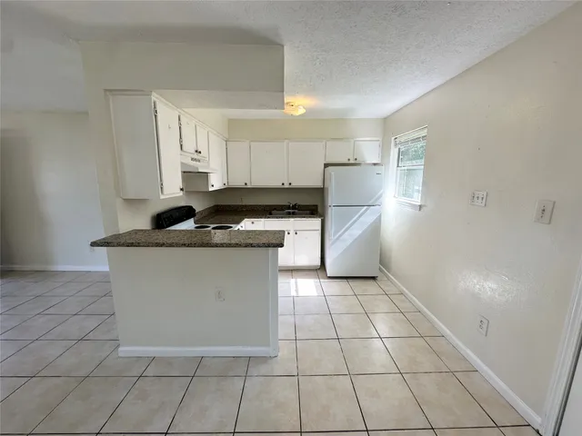 a kitchen with granite countertop a stove a sink and a refrigerator