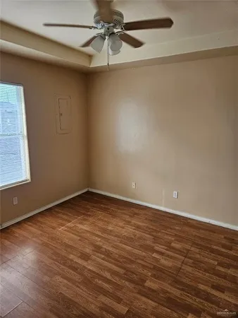 an empty room with a ceiling fan and wooden floor