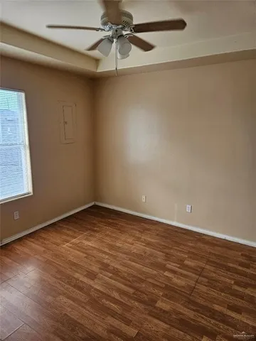 an empty room with a ceiling fan and wooden floor