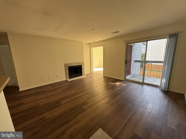 a view of empty room with wooden floor and fireplace