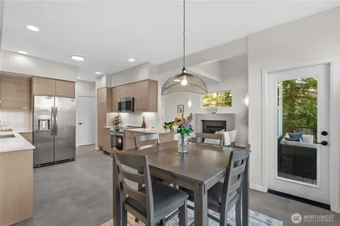 a kitchen with stainless steel appliances kitchen island granite countertop a refrigerator a stove a microwave oven a sink with a dining table and chairs