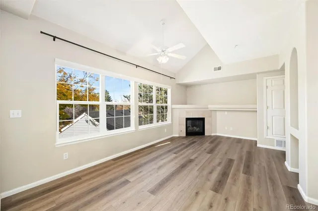 a view of a room with wooden floor fireplace and windows