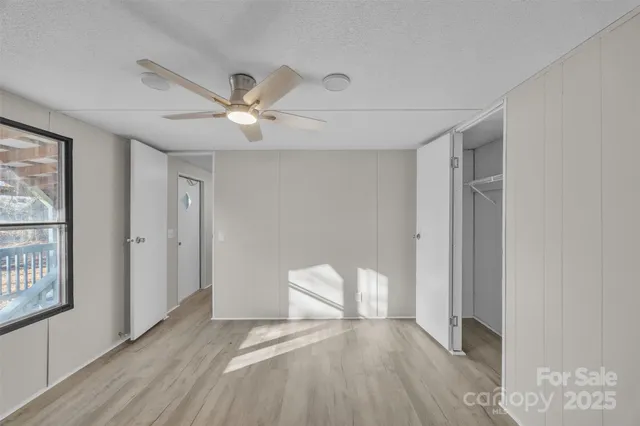 a view of empty room with wooden floor and fan