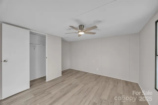 an empty room with wooden floor and ceiling fan