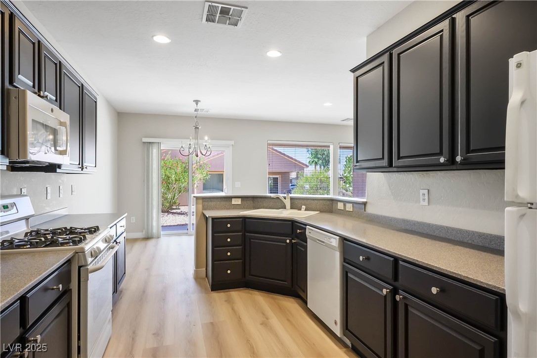 2563 Sargon Street Henderson, NV 89044 - Photo 12 of 35 Kitchen featuring white appliances, light wood finished floors, a chandelier, recessed lighting, and a peninsula