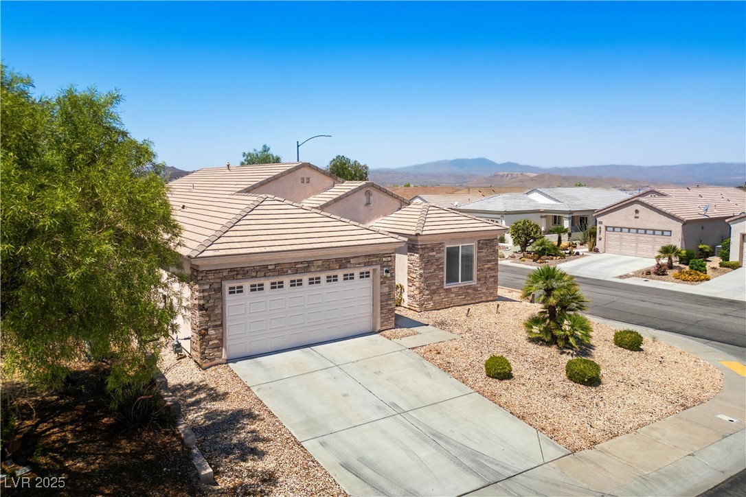 2563 Sargon Street Henderson, NV 89044 - Photo 24 of 35 Ranch-style house featuring stone siding, a garage, concrete driveway, a tile roof, and a mountain view
