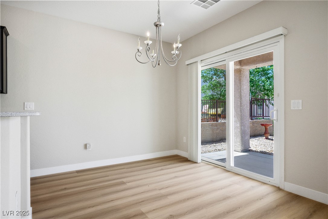 2563 Sargon Street Henderson, NV 89044 - Photo 9 of 35 Unfurnished dining area featuring light wood-style flooring and a chandelier