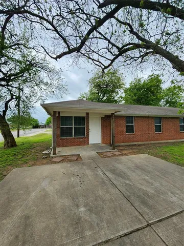 a front view of a house with a garden and trees