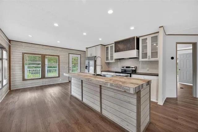 a large kitchen with stainless steel appliances granite countertop a stove a sink dishwasher and a large refrigerator with wooden floor