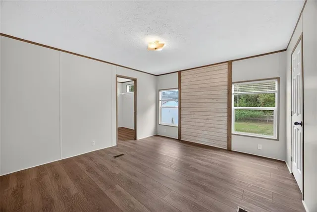 a view of an empty room with a window and wooden floor