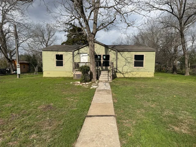 a front view of a house with a yard and trees