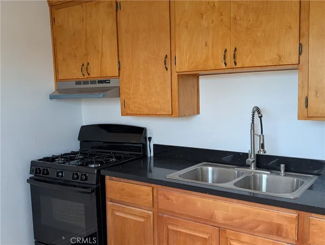 a kitchen with granite countertop a sink a stove and cabinets