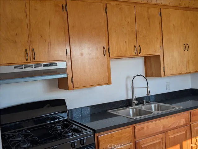 a kitchen with granite countertop a stove top oven cabinetry a sink and a window